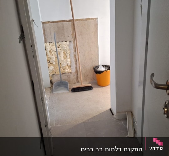 דלת פתוחה עם ידית מתכת ובריחים גלויים